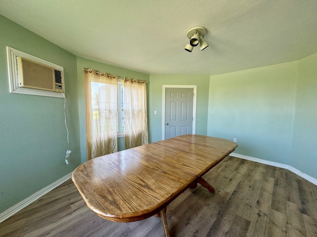 dining area featuring a wall unit AC, a textured ceiling, and hardwood / wood-style flooring