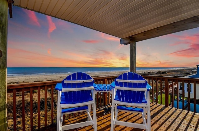 deck at dusk with a water view and a beach view