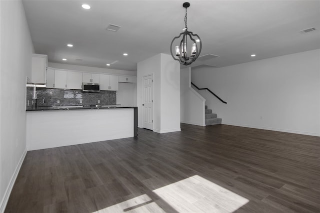 unfurnished living room with a chandelier and dark hardwood / wood-style flooring