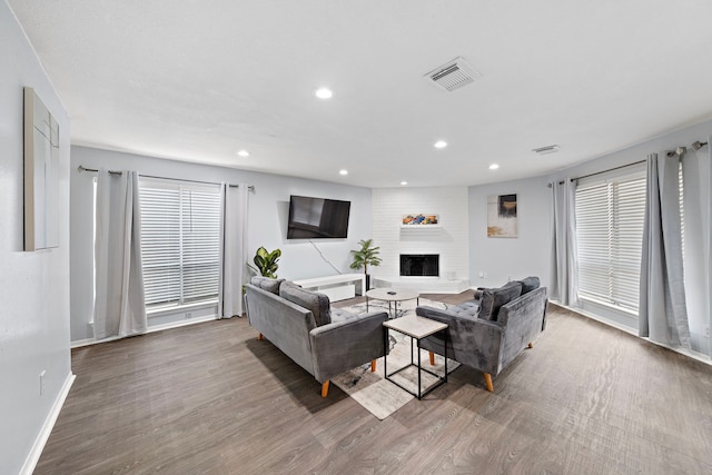 living room featuring wood-type flooring, brick wall, and a fireplace