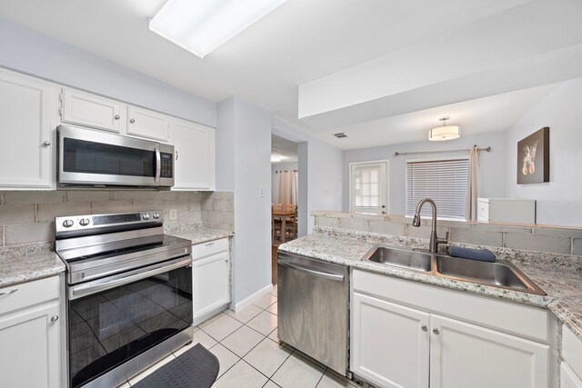 kitchen with white cabinets, backsplash, appliances with stainless steel finishes, and light tile patterned flooring