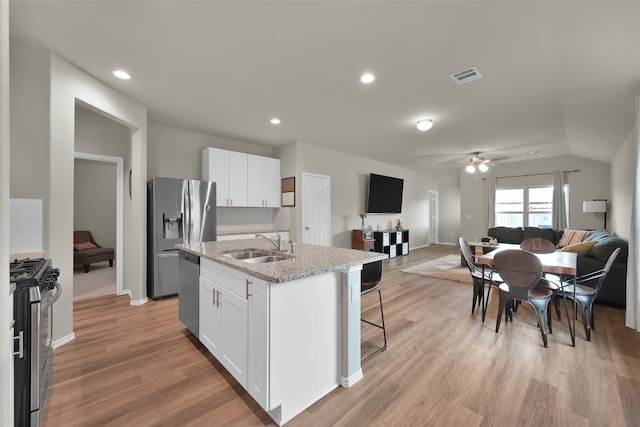 kitchen with ceiling fan, stainless steel appliances, white cabinets, light hardwood / wood-style floors, and a kitchen island with sink