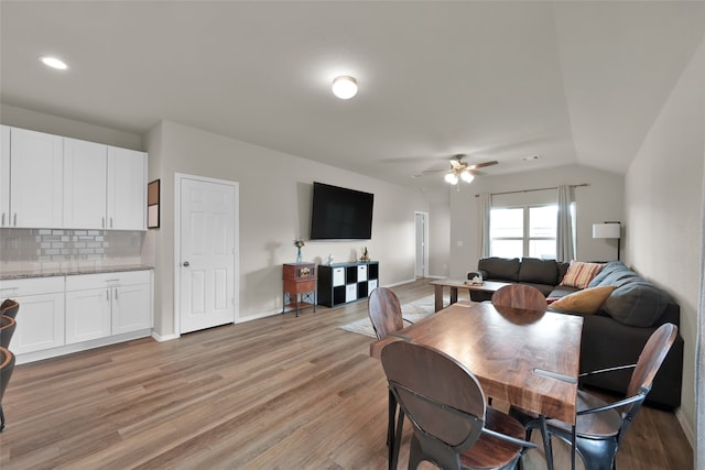 dining space with vaulted ceiling, ceiling fan, and light wood-type flooring