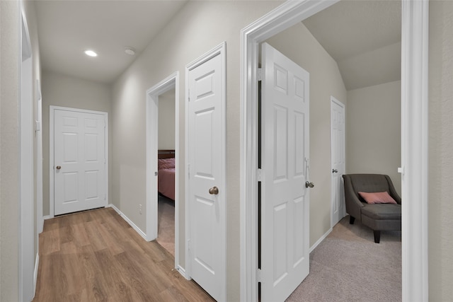 hallway featuring light colored carpet and vaulted ceiling