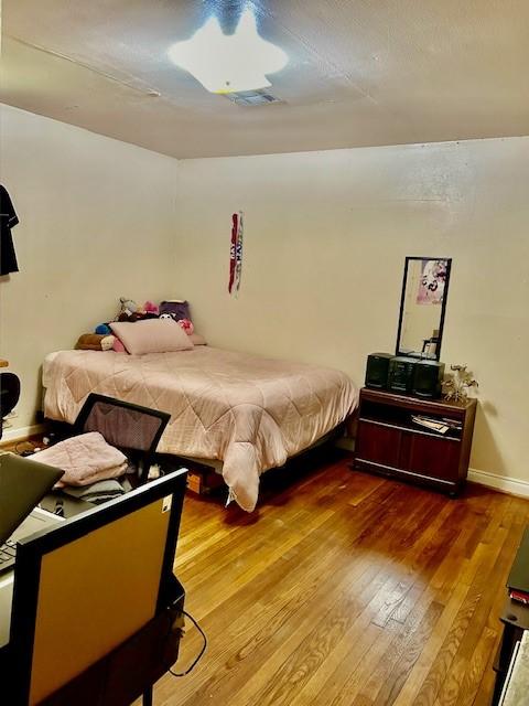 bedroom with a textured ceiling and wood-type flooring