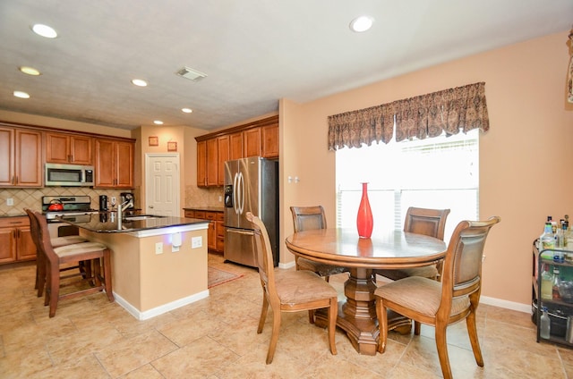 kitchen featuring tasteful backsplash, stainless steel appliances, sink, a breakfast bar area, and an island with sink