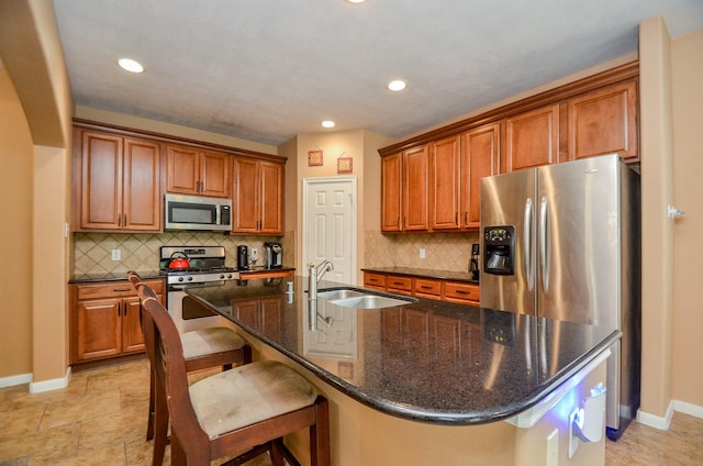 kitchen with a kitchen breakfast bar, stainless steel appliances, a kitchen island with sink, and sink