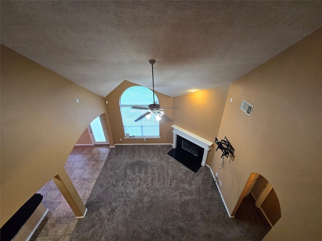 unfurnished living room featuring carpet floors, ceiling fan, high vaulted ceiling, and a textured ceiling