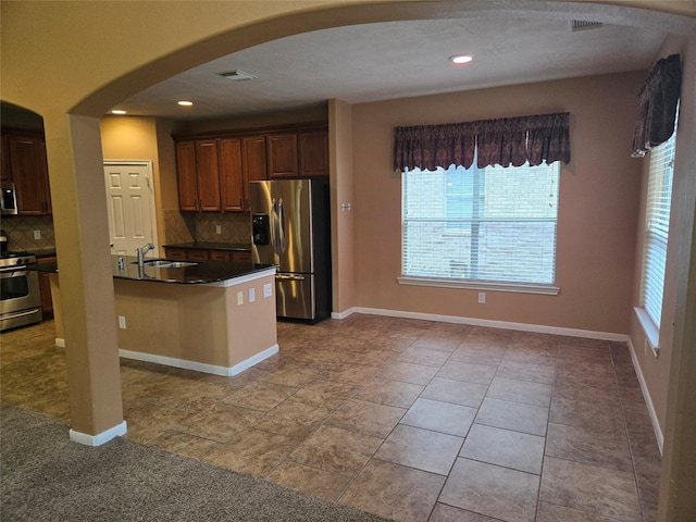 kitchen featuring kitchen peninsula, backsplash, stainless steel appliances, sink, and light tile patterned flooring