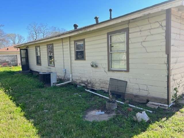 rear view of property with cooling unit and a lawn