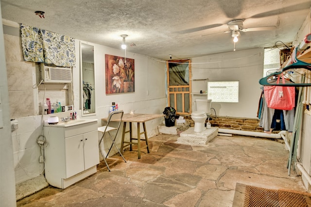 bathroom featuring vanity, a textured ceiling, toilet, cooling unit, and ceiling fan