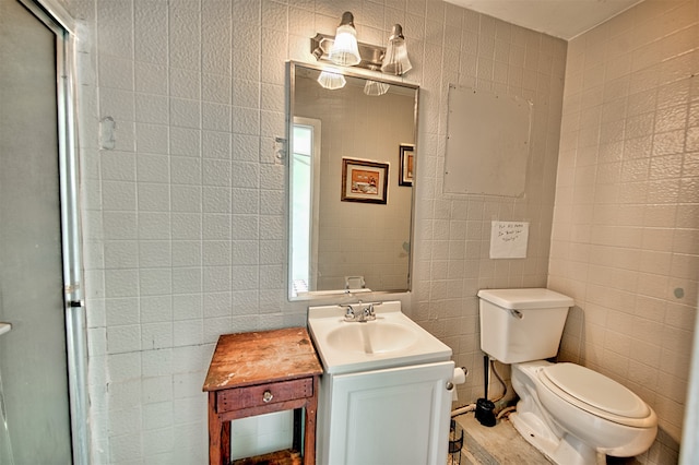 bathroom with vanity, walk in shower, tile walls, and toilet