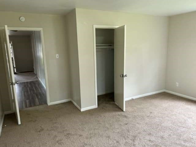 unfurnished bedroom featuring light carpet and a closet