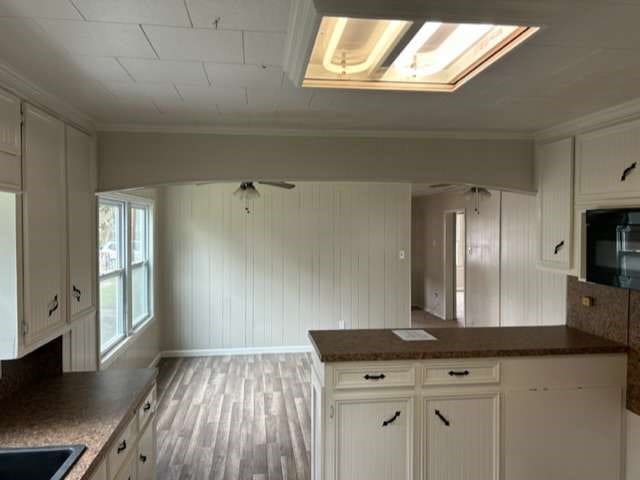 kitchen featuring hardwood / wood-style floors, oven, white cabinetry, ceiling fan, and ornamental molding