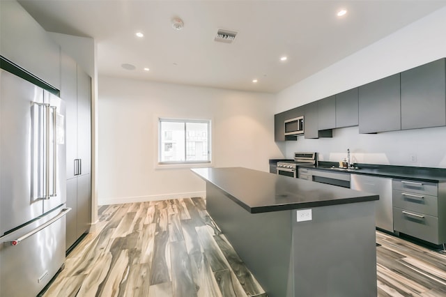 kitchen featuring a kitchen island, gray cabinetry, light hardwood / wood-style flooring, stainless steel appliances, and sink