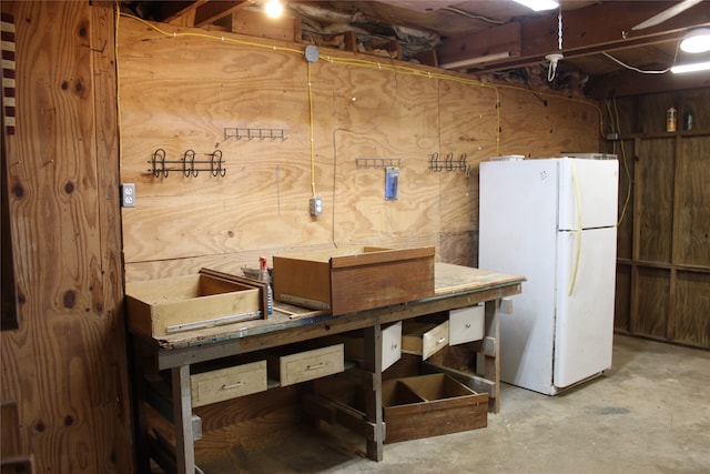 basement featuring white fridge and wood walls