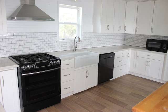 kitchen with white cabinets, backsplash, dark wood-type flooring, black appliances, and wall chimney exhaust hood