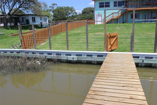 view of dock featuring a water view and a yard