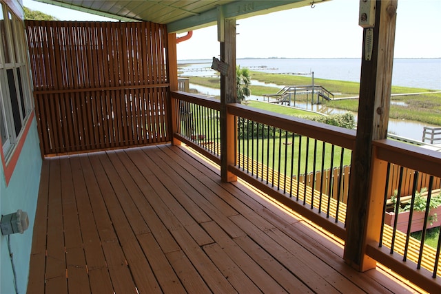 wooden deck with a water view and a lawn