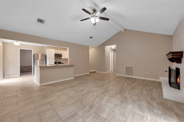 unfurnished living room featuring a fireplace, lofted ceiling with beams, and ceiling fan