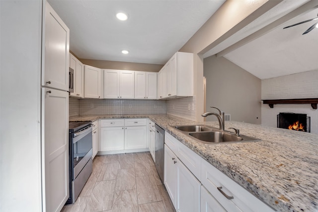 kitchen with a fireplace, appliances with stainless steel finishes, sink, and white cabinets