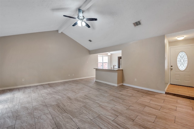 entrance foyer with a textured ceiling, ceiling fan, sink, and vaulted ceiling with beams