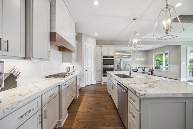 kitchen with appliances with stainless steel finishes, sink, hanging light fixtures, a notable chandelier, and a spacious island