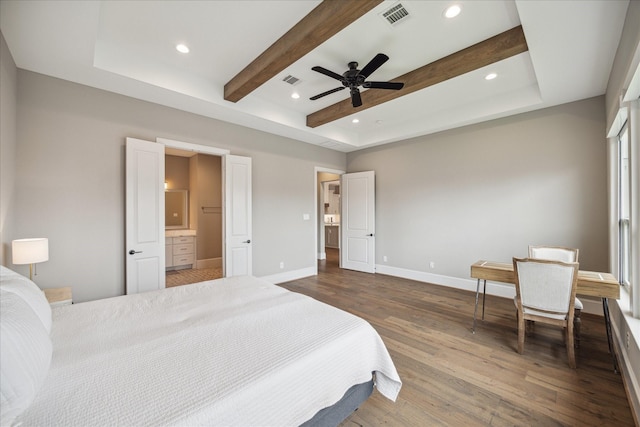 bedroom with a tray ceiling, connected bathroom, hardwood / wood-style flooring, and ceiling fan