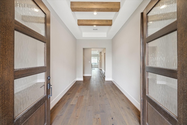 corridor with hardwood / wood-style floors and beamed ceiling