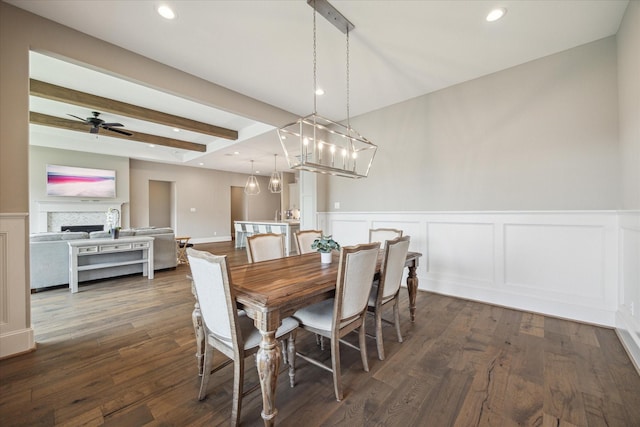 dining area with dark wood-type flooring, ceiling fan, and beam ceiling