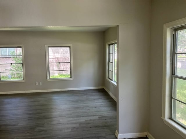 empty room with a wealth of natural light and dark hardwood / wood-style floors