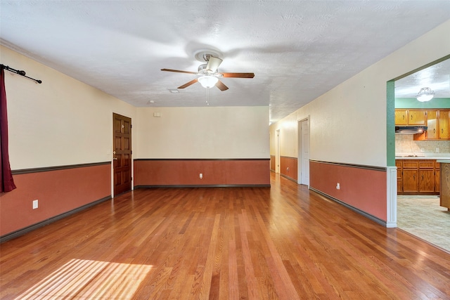 spare room featuring a textured ceiling, light hardwood / wood-style flooring, and ceiling fan