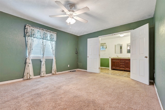 unfurnished bedroom with ceiling fan, light colored carpet, and a textured ceiling