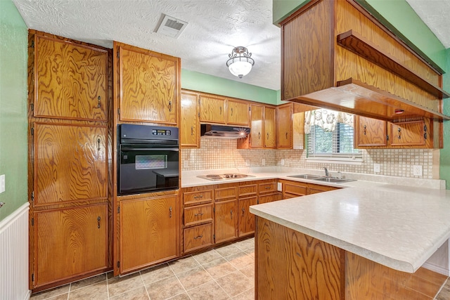 kitchen featuring white gas stovetop, extractor fan, kitchen peninsula, sink, and black oven