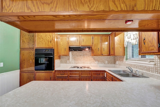 kitchen with white gas stovetop, tasteful backsplash, sink, and black oven