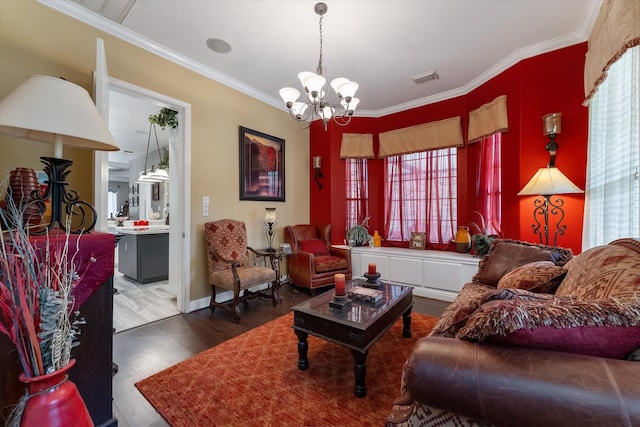 living room with an inviting chandelier, hardwood / wood-style floors, ornamental molding, and a healthy amount of sunlight