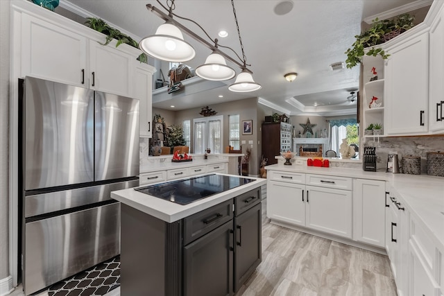 kitchen featuring stainless steel refrigerator, kitchen peninsula, decorative backsplash, and decorative light fixtures