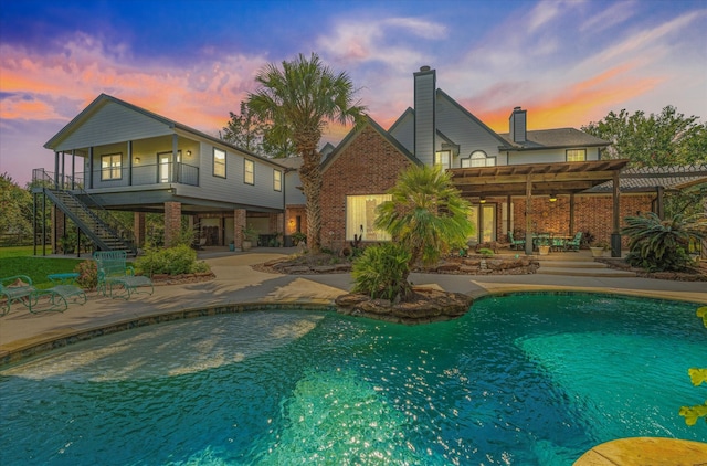 pool at dusk featuring a pergola and a patio area