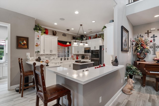 kitchen featuring kitchen peninsula, decorative backsplash, a kitchen bar, and hanging light fixtures