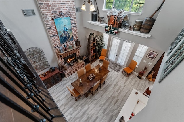 living room featuring a fireplace, light hardwood / wood-style floors, a high ceiling, and brick wall