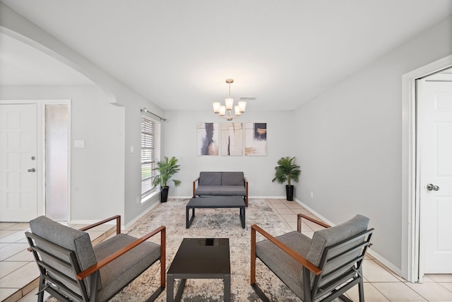 living area featuring light tile patterned floors, baseboards, arched walkways, and an inviting chandelier