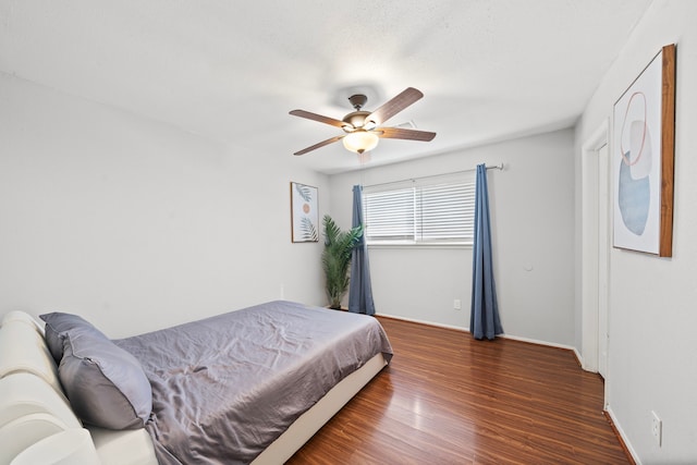 bedroom with ceiling fan, wood finished floors, and baseboards