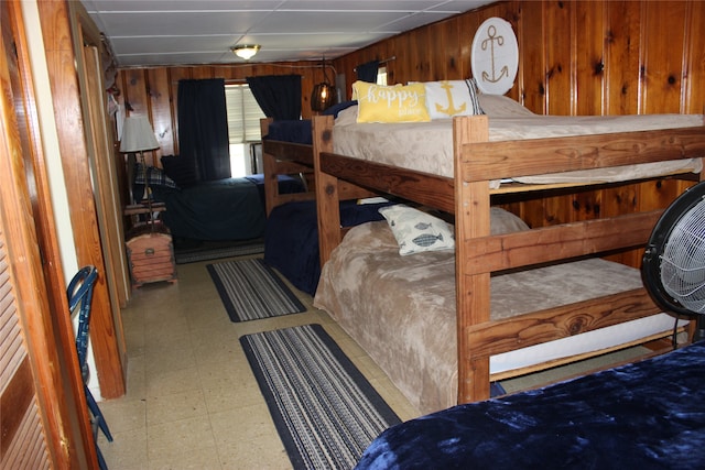 bedroom with a paneled ceiling, tile patterned floors, and wooden walls