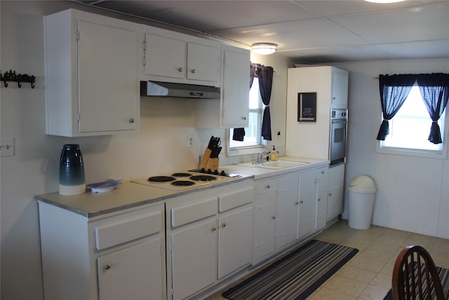 kitchen featuring light tile patterned flooring, white cabinetry, stainless steel oven, and a wealth of natural light