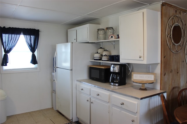 kitchen with light tile patterned flooring, white fridge, and white cabinets