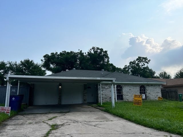 ranch-style home with a carport and a front yard