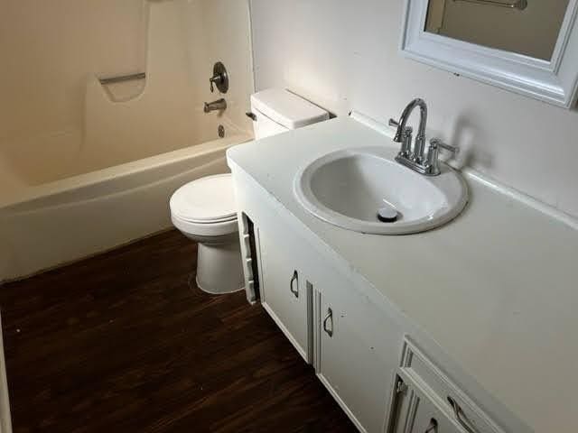 full bath with vanity,  shower combination, wood finished floors, and toilet