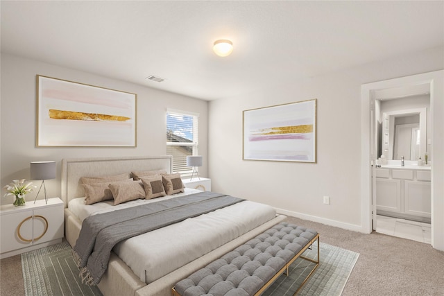 bedroom with ensuite bathroom, carpet flooring, and sink