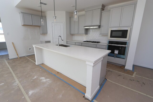 kitchen featuring a center island with sink, oven, sink, and built in microwave