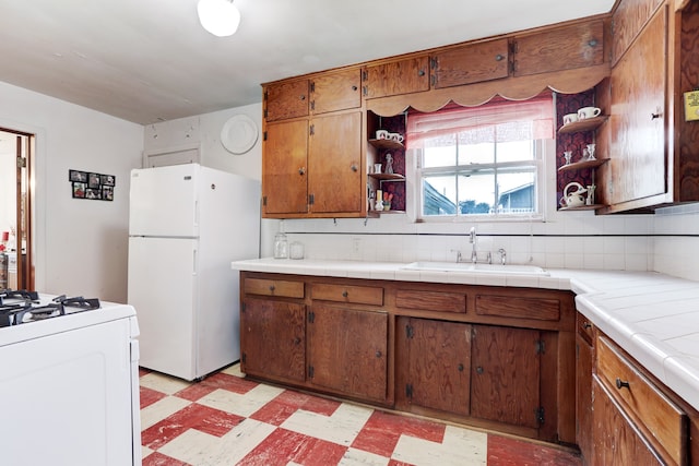 kitchen featuring tile counters, white appliances, light tile patterned floors, backsplash, and sink